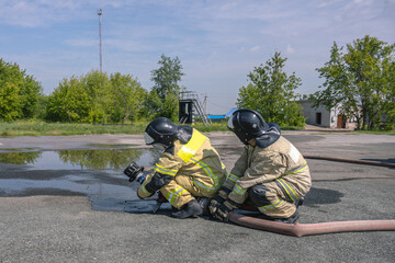 Firefighters are holding a hydraulic monitor in their hands. Firefighters extinguish the fire....