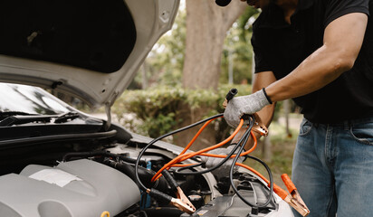 Jumpstarting Success: A close-up shot of a man's hands connecting jumper cables to a car battery, capturing the focus and determination needed to get back on the road.  