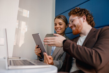 Two enthusiastic professionals share a productive moment while using digital devices in a...
