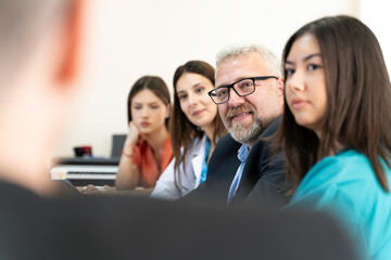 A group of people are sitting at a table with laptops and a projector. They are likely discussing a project or presentation