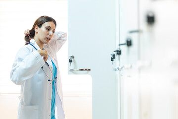 Young female doctor in a changing room putting his clothes to the locker
