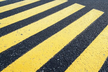 Under bright daylight, yellow and black pedestrian zebra crosswalk markings appear on fresh asphalt