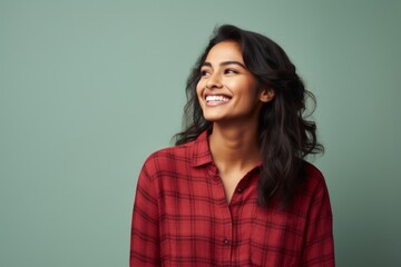 Obraz premium Portrait of a happy indian woman in her 20s dressed in a relaxed flannel shirt in solid color backdrop
