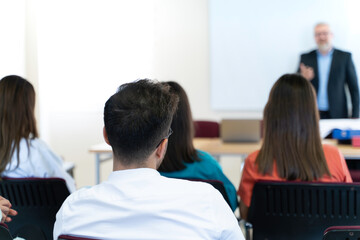 A group of people are sitting at a table with laptops and a projector. They are likely discussing a project or presentation
