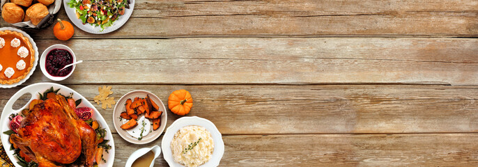 Thanksgiving turkey dinner. Top view corner border on a rustic wood table banner background. Turkey, mashed potatoes, stuffing, pumpkin pie and sides.