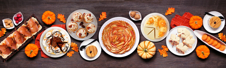 Autumn desserts table scene with a variety of gourmet fall sweet foods. Top view over a dark wood banner background. © Jenifoto