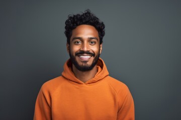 Portrait of a glad indian man in his 20s wearing a thermal fleece pullover in front of solid color backdrop