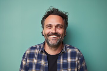 Portrait of a grinning man in his 40s wearing a comfy flannel shirt in solid pastel color wall