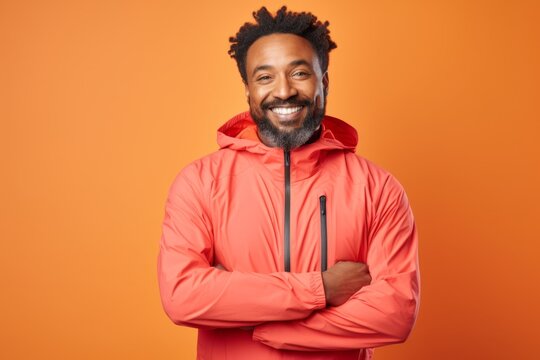 Portrait of a glad afro-american man in his 40s wearing a windproof softshell in front of solid pastel color wall