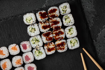 Elegant Hosomaki Sushi Set with Soy-Glazed Rolls on Slate Plate in Minimalist Black and White Color Scheme