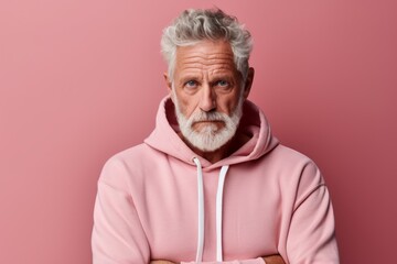 Portrait of a content man in his 60s sporting a comfortable hoodie over solid pastel color wall