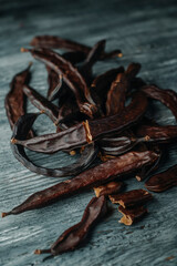 ripe carob pods on a wooden table