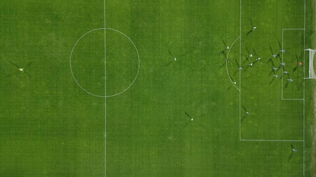 Drone footage of a football match from a top-down view, showcasing players on the pitch during an intense play near the goal, offering a unique aerial perspective