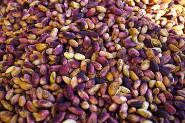 Freshly harvested pistachios for sale at a market in Gaziantep's Old Town: close-up photo of raw unpeeled nuts with pink and purple skins. Product from Turkish fields at the bazaar