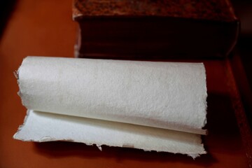 A roll of parchment, an old sheet of paper on the table