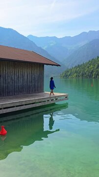 Breathtaking view of Lake Plansee in Tyrol, Austria, featuring serene waters and majestic mountain backdrop. woman at a boathouse by the lake