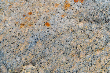 Texture of natural beige granite with black dots.