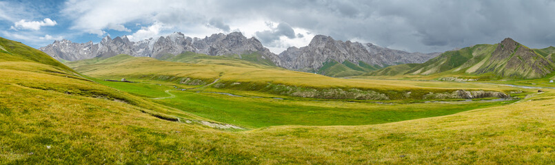 panorama of wide green valley in highlands of kyrgyzstan high mountains in the background