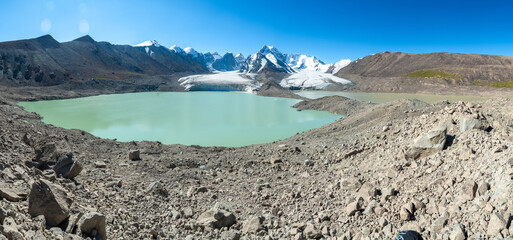 Panorama of the foothills of Mount Kyzylasker, a glacier with a moraine blue lake in the highlands....