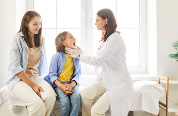 Obraz premium Dentist doctor or nurse conducts an examination on boy patient at the clinic. Boy mother is present during the medical treatment, as the healthcare professional provides dentistry care for the child.