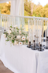 The table of the bride and groom decorated with flowers and candles. Wedding banquet of the newlyweds. Beautiful decor in the form of candles and white flowers on the table of the bride and groom