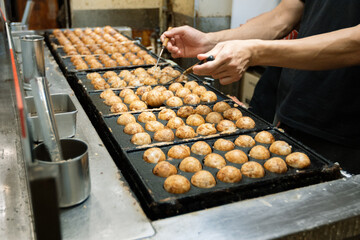 A japanese chef cooking takoyaki, a popular street food in Osaka, Japan