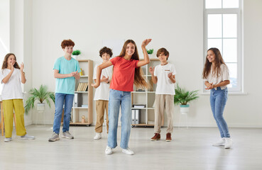 Obraz premium Group of students enjoys their leisure time by dancing and playing together in a school classroom. The children are happy and full of energy, having fun during a break from studies.