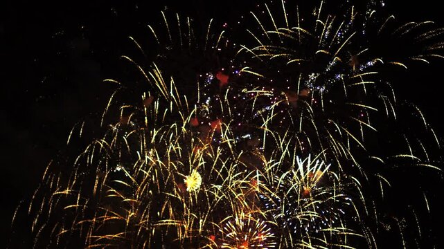 Golden red lilac sparks scattering fireworks on the black night sky. General plan