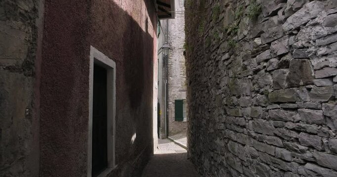 Narrow street in shadow in Varenna. Walking through narrow authentic streets in Italy. Travel, vacation, holidays in Italy