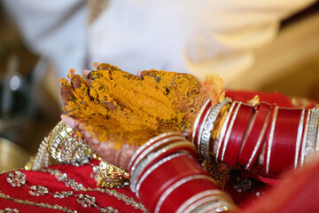 Bride and groom's hands adorned with intricate henna designs and vibrant bangles, during a traditional Indian wedding ritual.