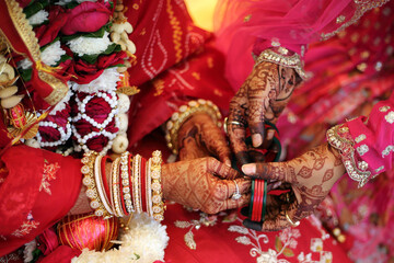 Indian wedding moment, with hands adorned in intricate henna designs, vibrant red bangles, and...