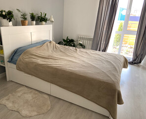 Scandinavian design bedroom with minimalist style and natural light. Home plants and simple cozy bed
