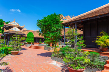 Vietnamese courtyard with trees, a fountain and houses covered with tiles