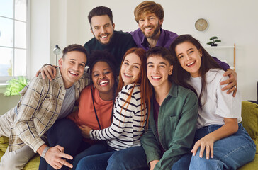Fototapeta premium Young people having fun together. Portrait of smiling happy group of multiracial best friends hanging out together at home party. Friends pose together looking at camera. Concept of friendship.