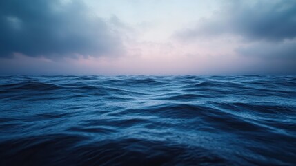 An image of dark, rolling ocean waves under a moody sky with clouds at dusk, creating a dramatic and slightly ominous atmosphere.