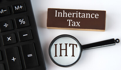 INHERITANCE TAX - words on a brown wooden block with a calculator and magnifying glass in the...