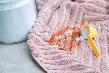 Close up of washing powder and a dirty pink towel with red stain on grey table. Cloth stain remover...