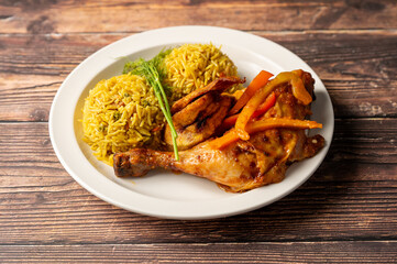 Caption: Tasty Caribbean food served on a white plate or white bowl on a rustic vintage wooden table backdrop - colorful home cooked meals and desserts with chicken, chips, vegetables, rice, bbq, stew