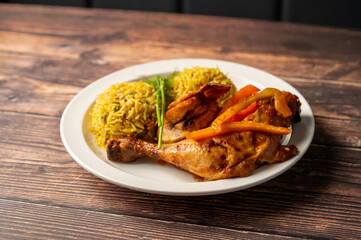Caption: Tasty Caribbean food served on a white plate or white bowl on a rustic vintage wooden table backdrop - colorful home cooked meals and desserts with chicken, chips, vegetables, rice, bbq, stew
