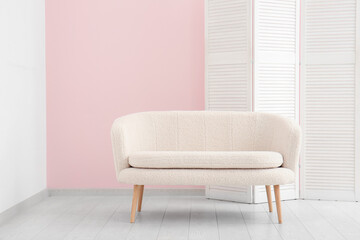 Folding screen and white sofa near pink wall