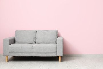 Cozy grey sofa near pink wall