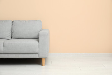 Cozy grey sofa near beige wall