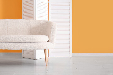 Folding screen and white sofa near orange wall
