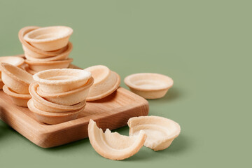Wooden board with homemade tartlets on green background