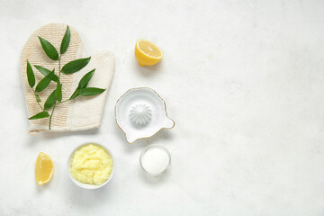 Bowl of lemon body scrub with massage glove and juicer on white background
