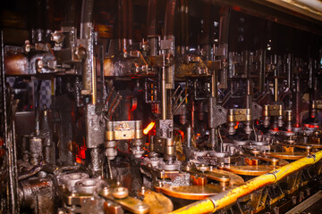 Glass factory, production of glass containers. Molten glass is blown into molds. Robotics in industry. Modern technologies, robotic machines produce products. Technological work at the plant.