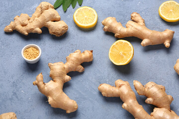 Fresh ginger roots with slices of lemon and leaves on blue background