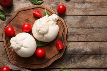 Board with tasty Burrata cheese on wooden background