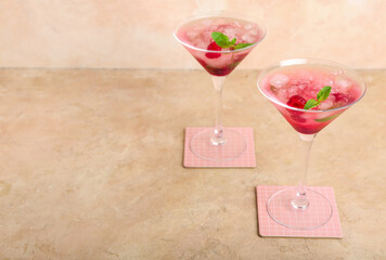 Glasses of fresh raspberry mojito on beige background