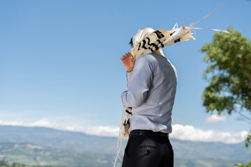 A young Jewish man throws the right corners of the tallit over his left shoulder to begin the...